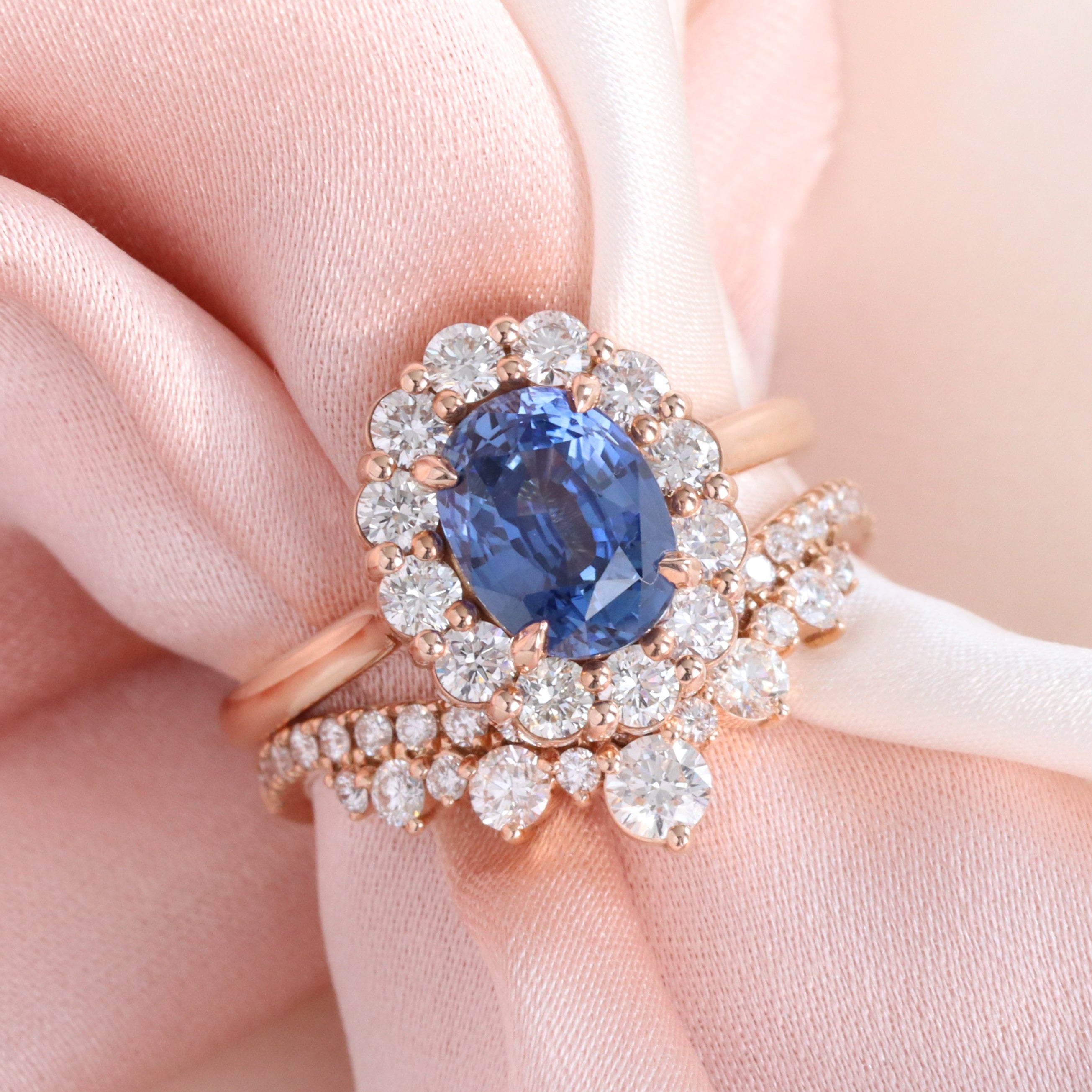 Rose gold sapphire and diamond bridal set featuring oval blue sapphire halo engagement ring with matching diamond wedding band La More Design Jewelry