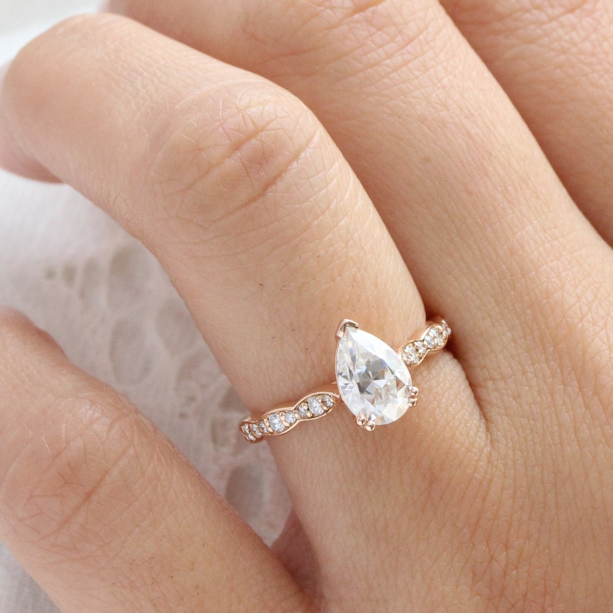 Solitaire pear moissanite engagement ring in rose gold scalloped diamond band by la more design
