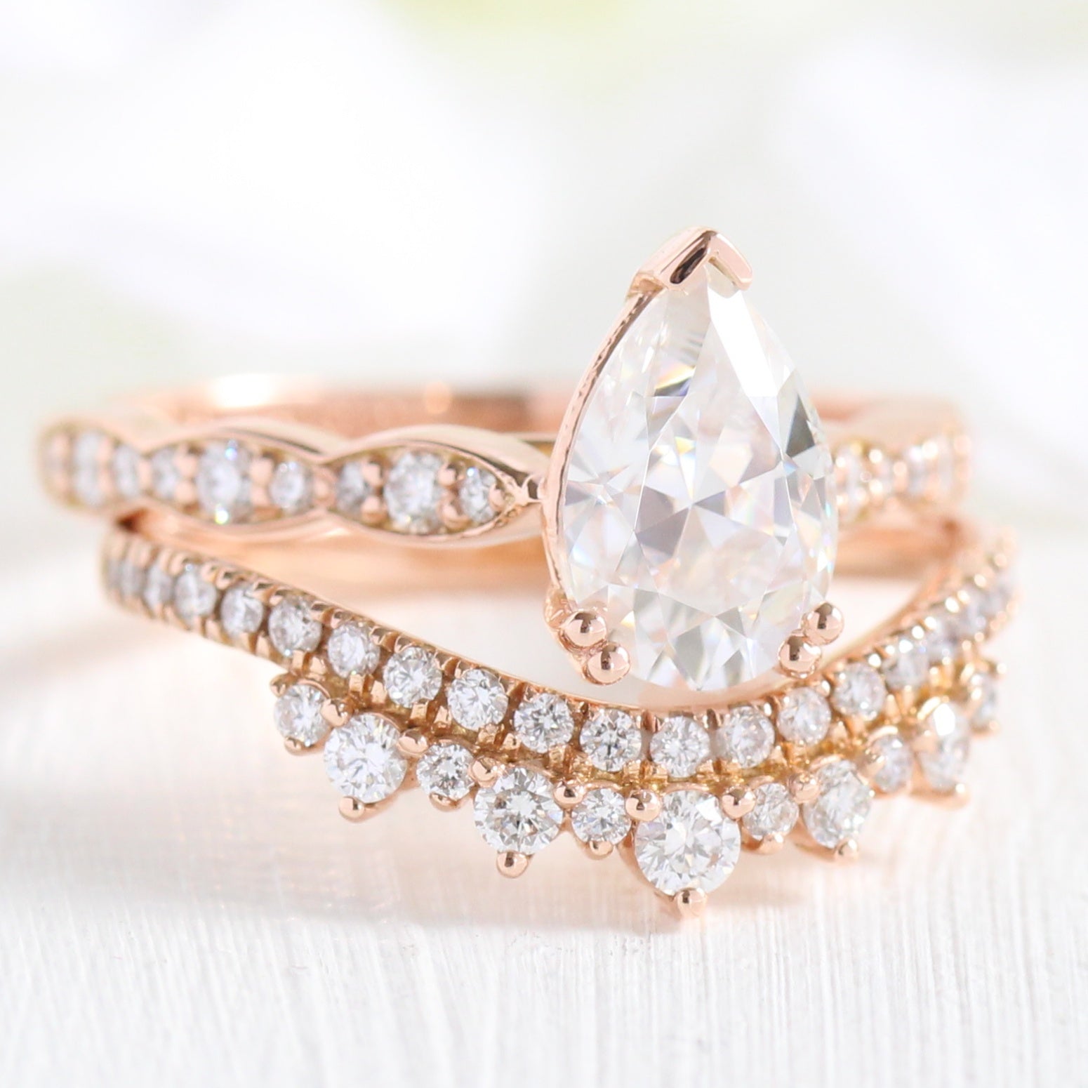Solitaire pear moissanite ring and curved crown diamond wedding band in rose gold bridal set by la more design jewelry