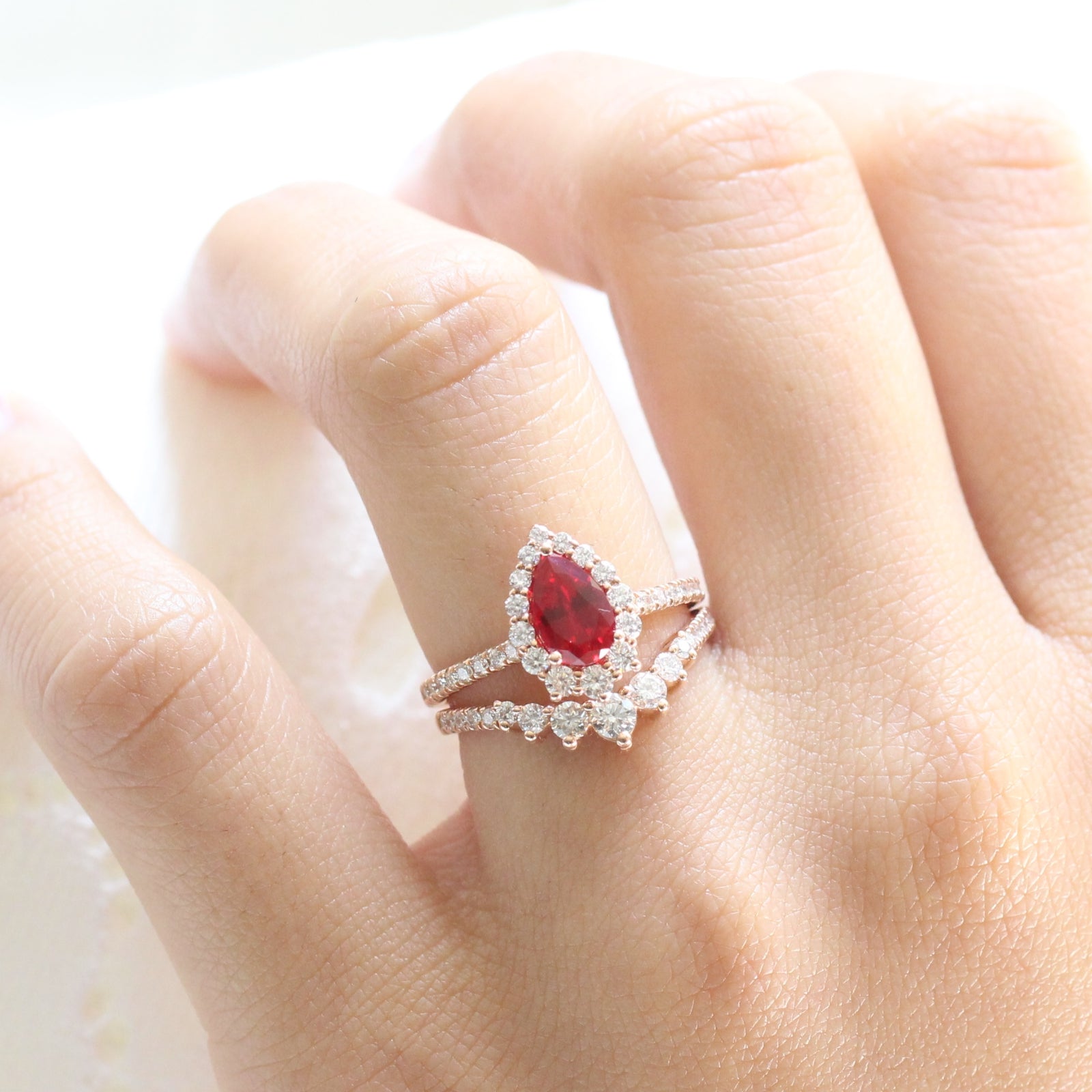 halo diamond ruby engagement ring rose gold pear shaped ring and pave diamond wedding band by la more design jewelry