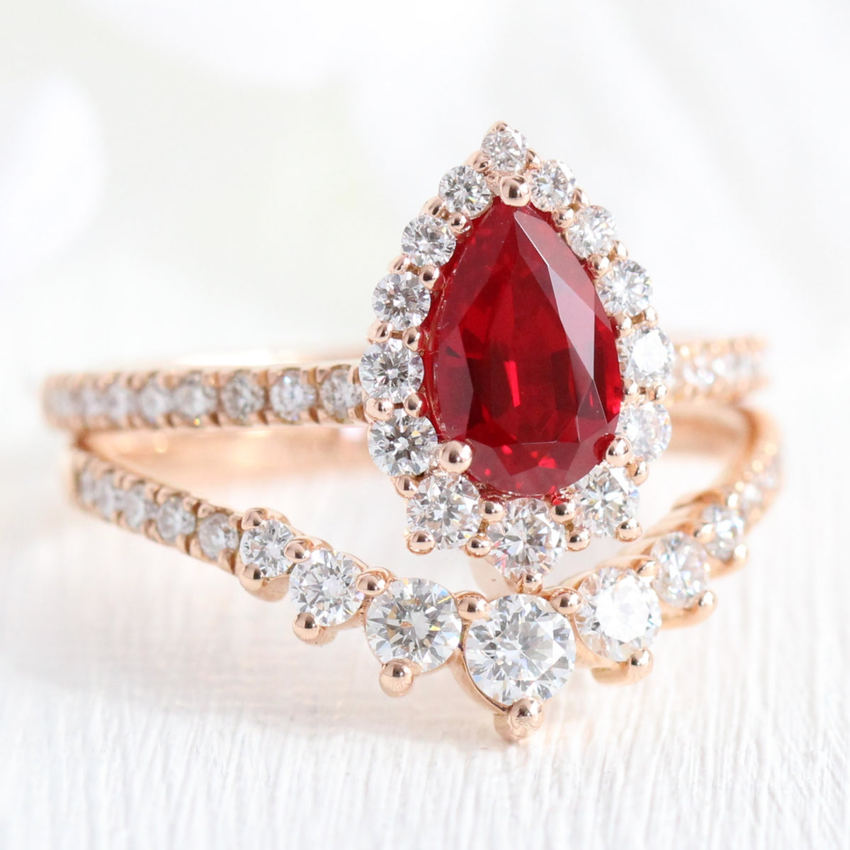 halo diamond ruby engagement ring rose gold pear shaped ring and pave diamond wedding band by la more design jewelry