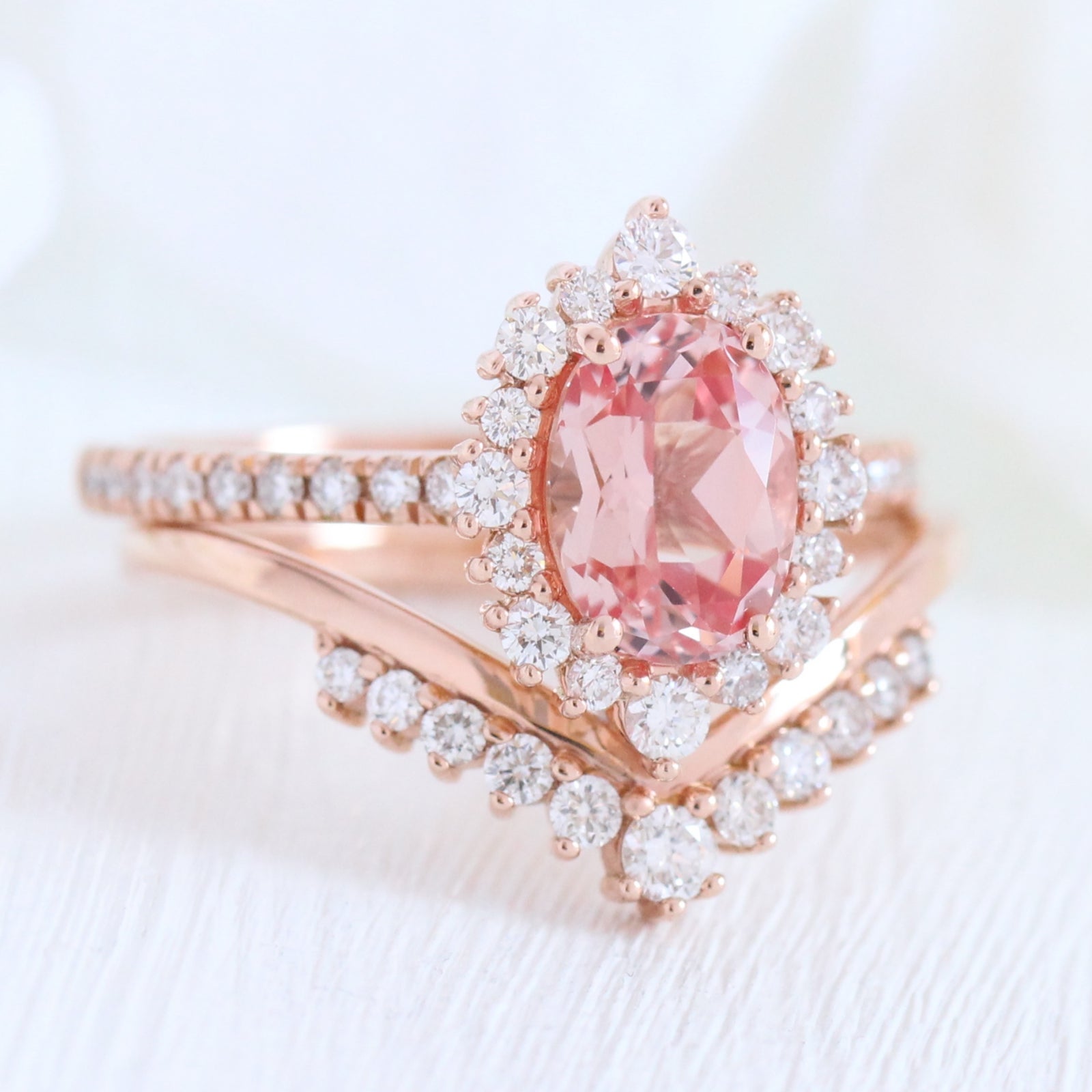 oval peach sapphire engagement ring rose gold halo diamond bridal set and curved diamond wedding band by la more design jewelry