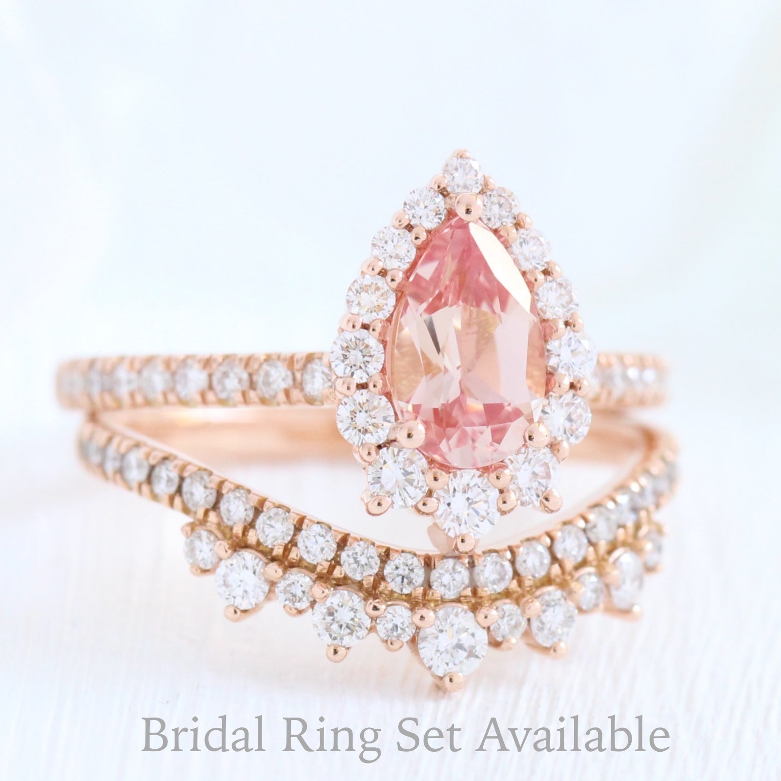 pear shaped peach sapphire engagement ring rose gold and curved crown diamond wedding band by la more design jewelry