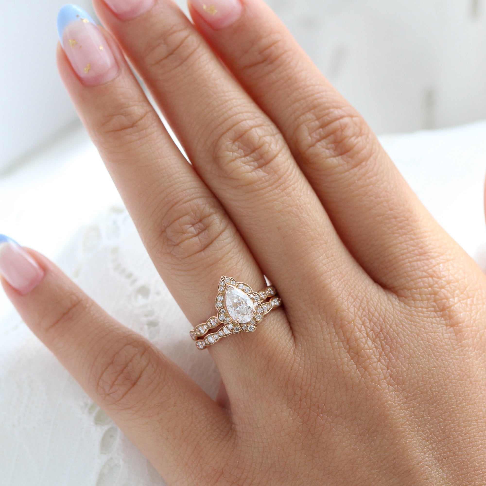 vintage inspired pear moissanite ring and matching diamond wedding band in rose gold bridal set by la more design jewelry